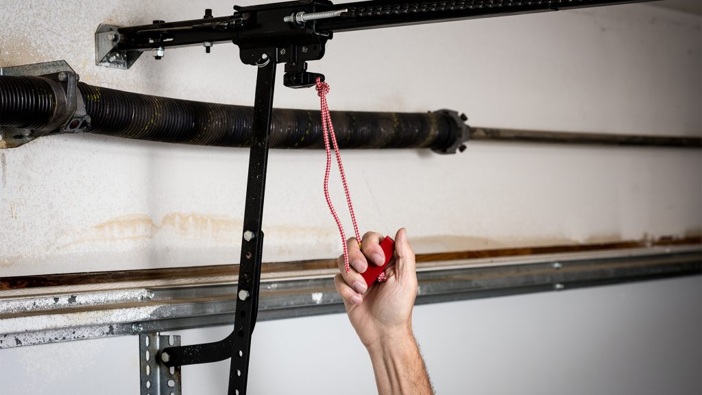 Person manually opening garage door using emergency release cord