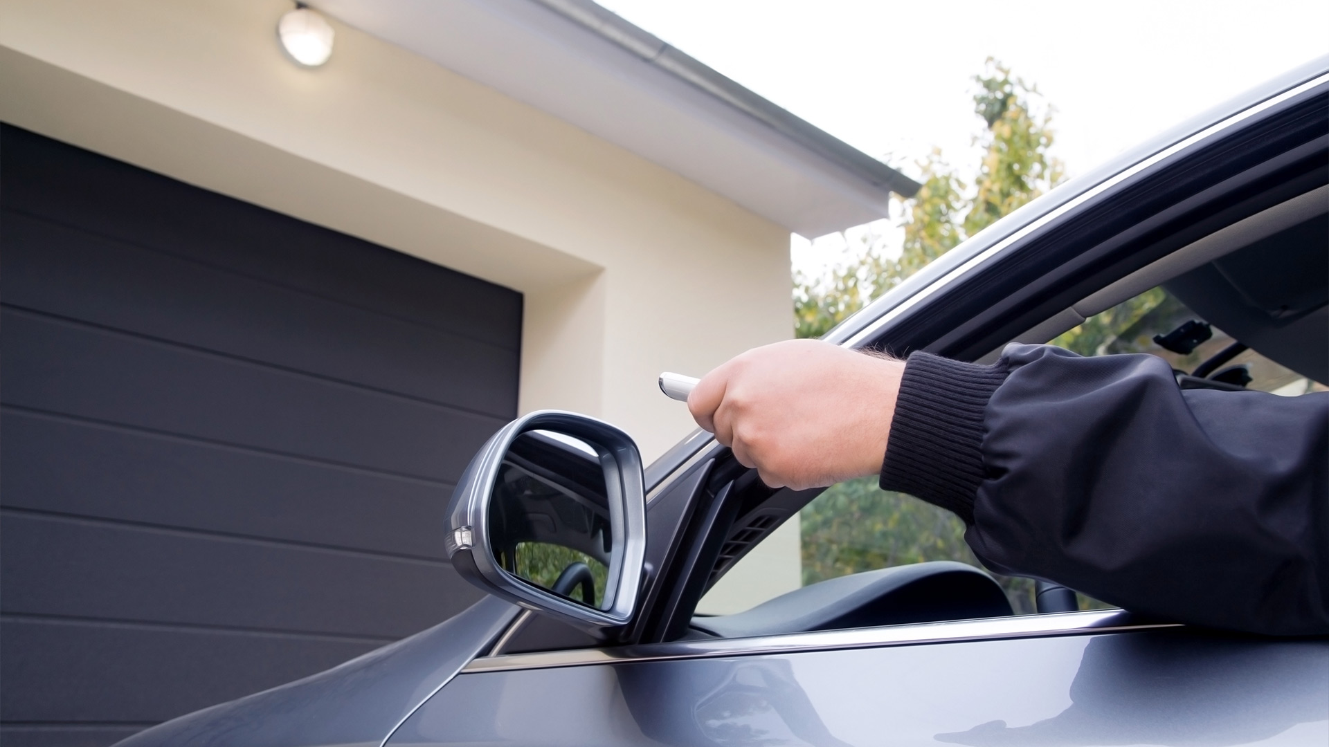 man in car opening automatic garage door with remote control