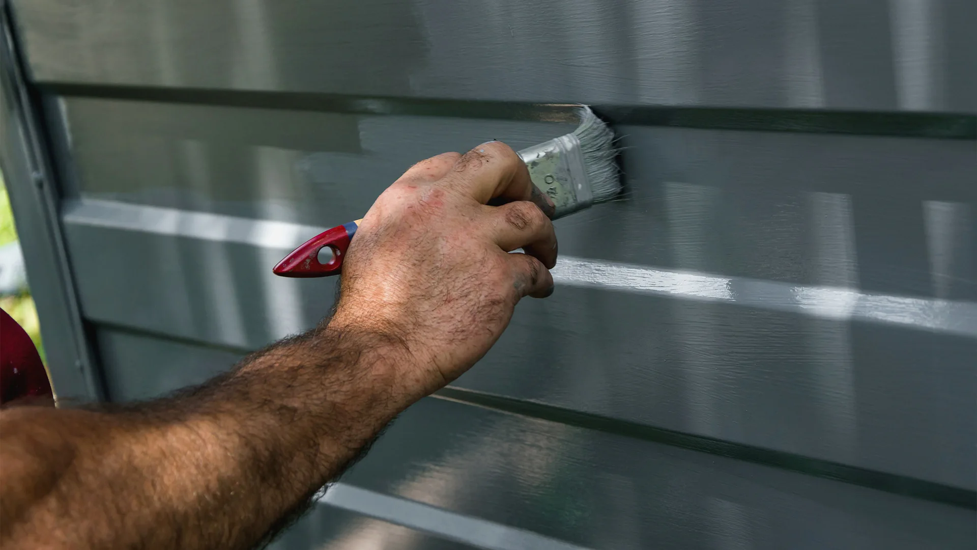 person painting garage door in grey