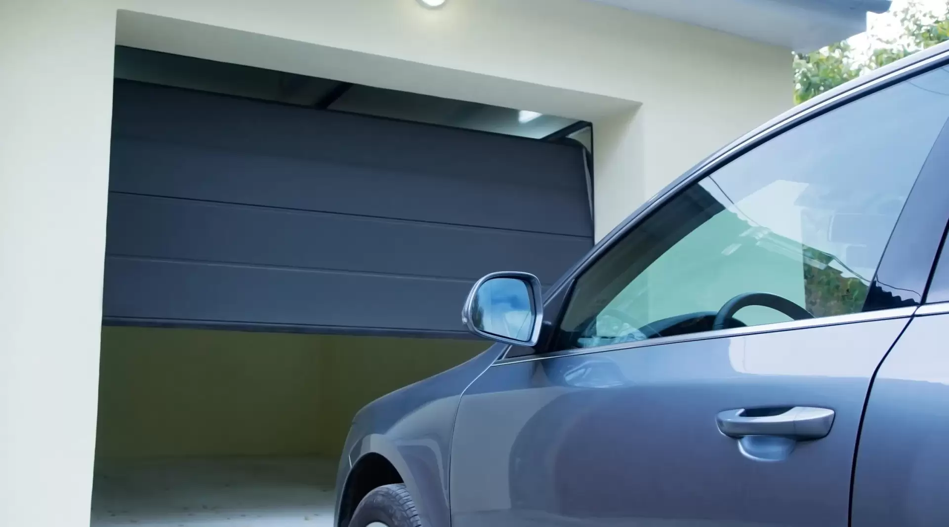 Black garage door with a dark blue car waiting to enter